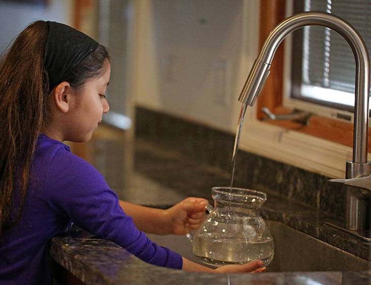 girl filling pitcher of water
